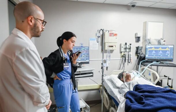 DNP acute care student Alexis Murray, under the watchful eye of Dr. Chris Doneski, talks with a patient’s daughter during the AI simulation. 